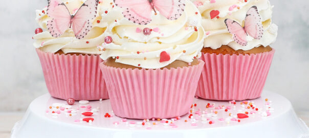 Cupcakes in pinken Muffinformen mit rosa Schmetterlingen