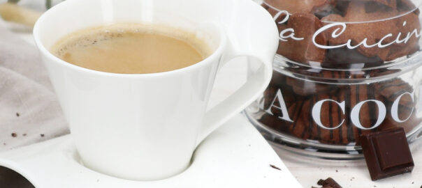 Das Bild zeigt eine Tasse Kaffee mit Schokoknusperkeksen