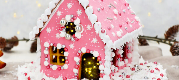 Das Bild zeigt ein pinkes Lebkuchenhaus mit zuuckersüßen Dekorationen.
