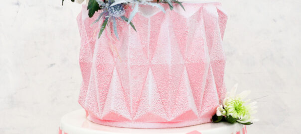 Das Bild zeigt einen winterlichen Origami-Cake in zartem Rosa mit Dekorationen.