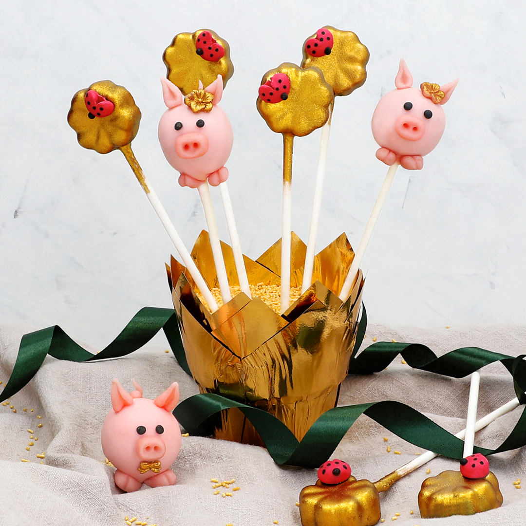 Das Bild zeigt süße Glücksbringer Cake-Pops und niedliche Glücksschweinchen.