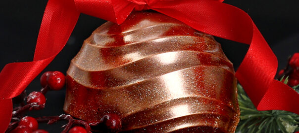 Das Bild zeigt eine goldene Weihnachtskugel aus Schokolade mit einer Schleife.