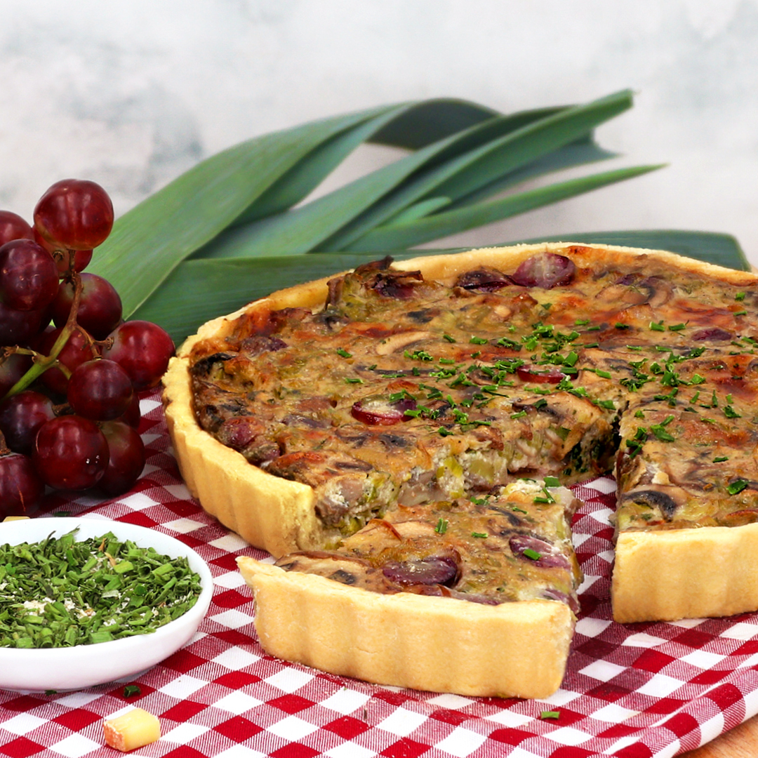 Das Bild zeigt eine köstliche vegetarische Quiche mit Weintrauben und Pilzen.