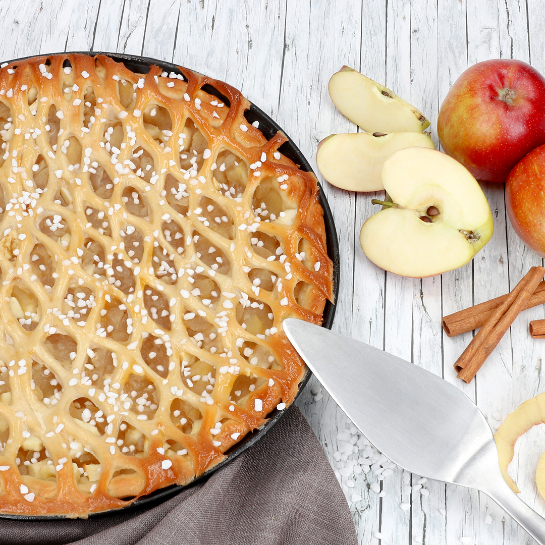 Das Bild zeigt einen Apfelkuchen mit einem Gitterroller