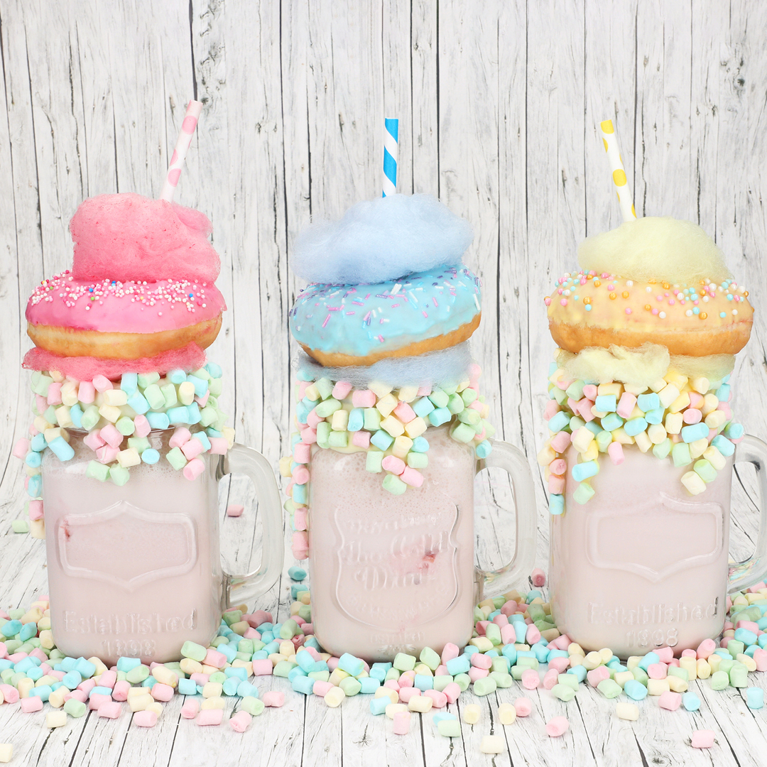 Das Bild zeigt 3 Milkshakes die mit Donuts und Zuckerwatte dekoriert wurden