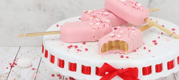 Das Bild zeigt rosa farbende Cakesicles und Macarons