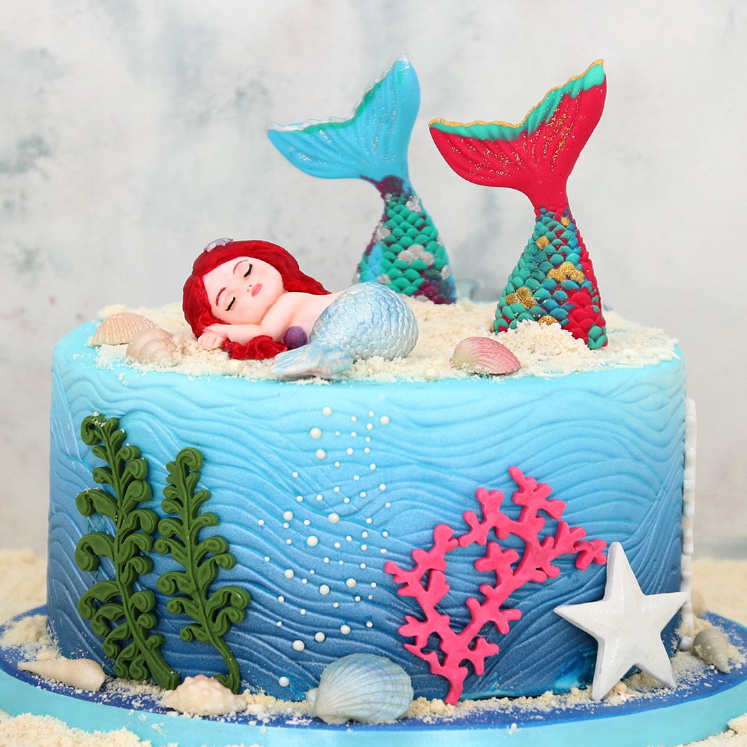 Das Bild zeigt eine Torte im Unterwasser-Stil mit einer Meerjungfrau aus Fondant