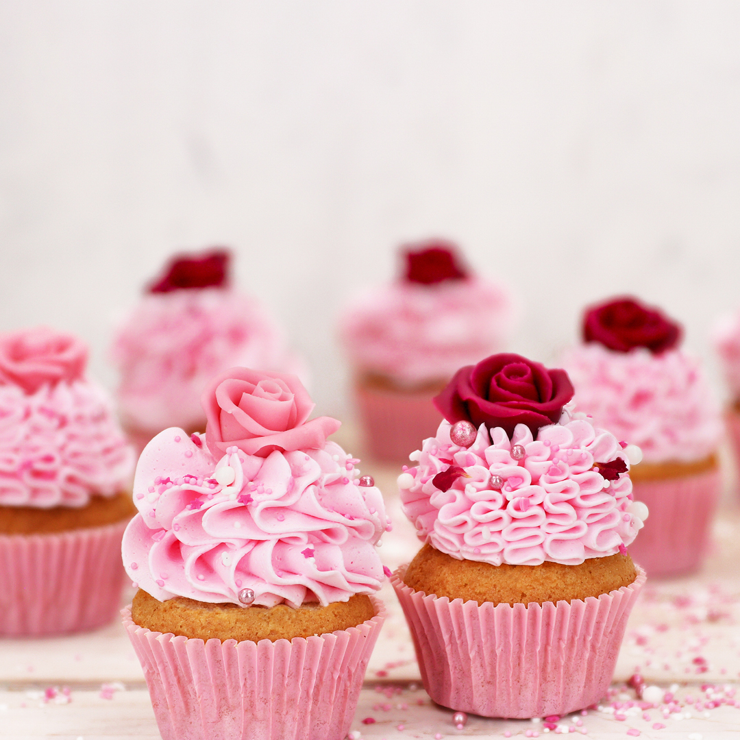 Das Bild zeigt Cupcakes die mit Marzipan-Rosen dekoriert wurden.