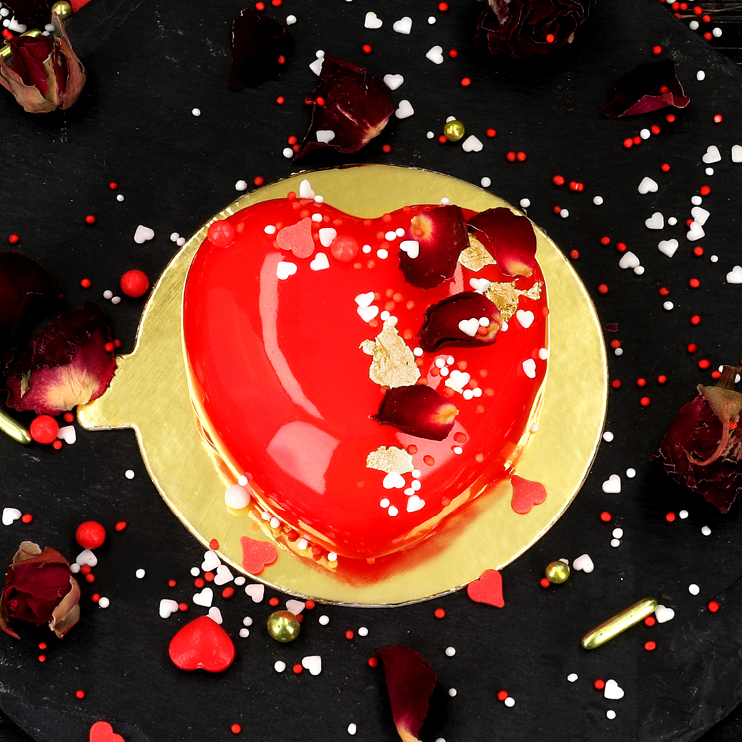 Das Bild zeigt ein Törtchen in Herzform, welches mit Mirror Glaze überzogen wurde