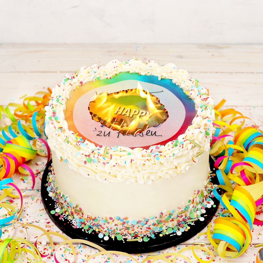 Das Bild zeigt eine Torte, bei der die oberste Schicht abbrennt, um die darunter liegende Botschaft zu enthüllen